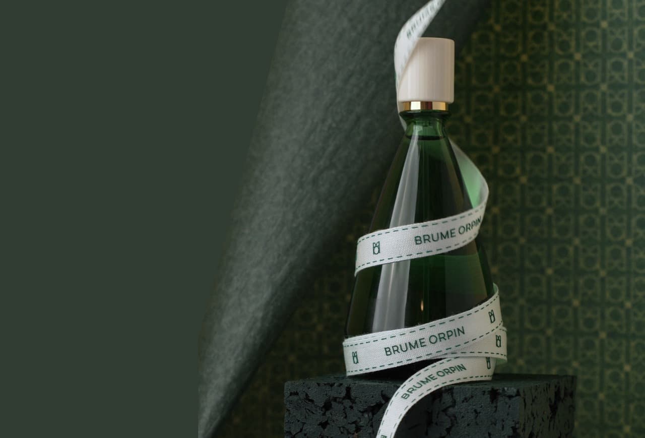 Un flacon BRUME ORPIN entouré d'un ruban blanc BRUME ORPIN