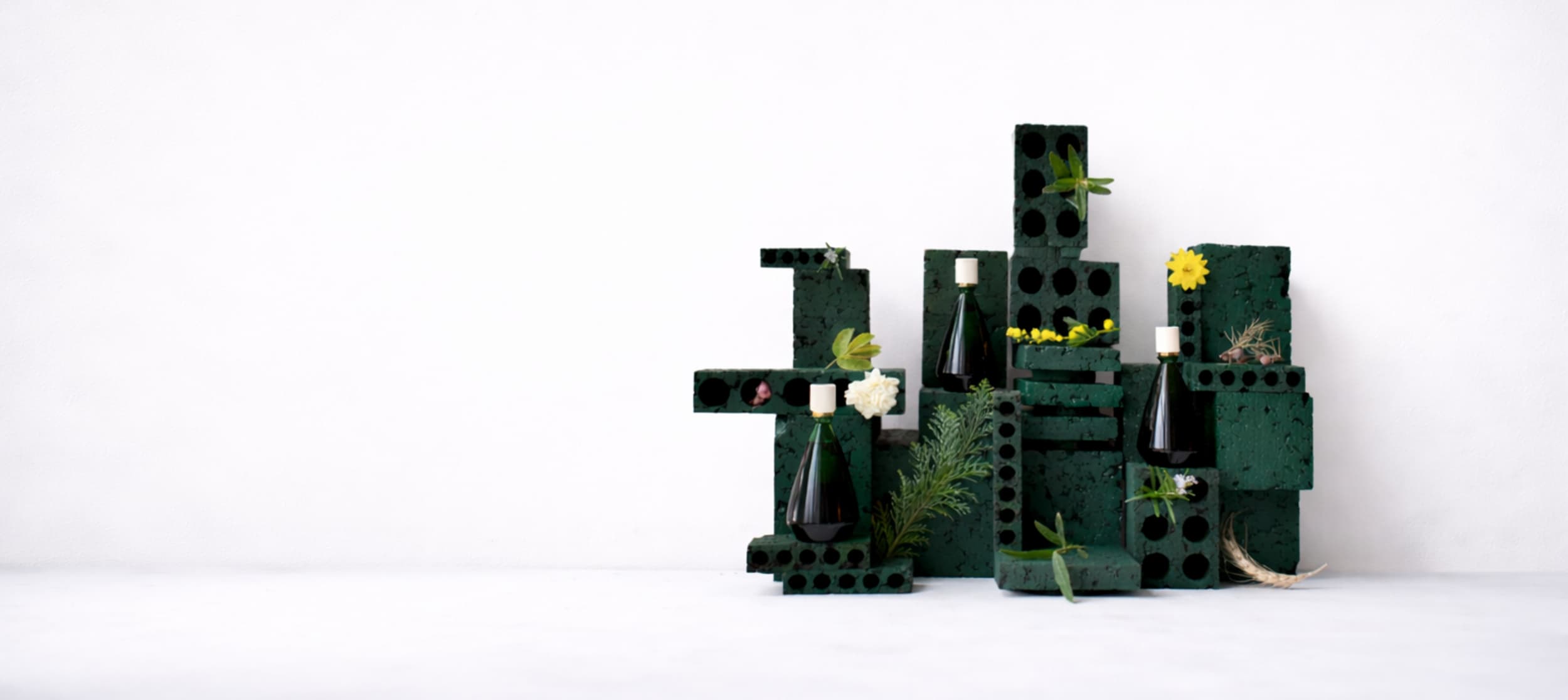 Des flacons de parfums Brume Orpin sur leurs présentoirs avec des fleurs et des feuilles