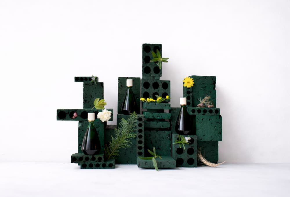 Des flacons de parfums Brume Orpin sur leurs présentoirs avec des fleurs et des feuilles